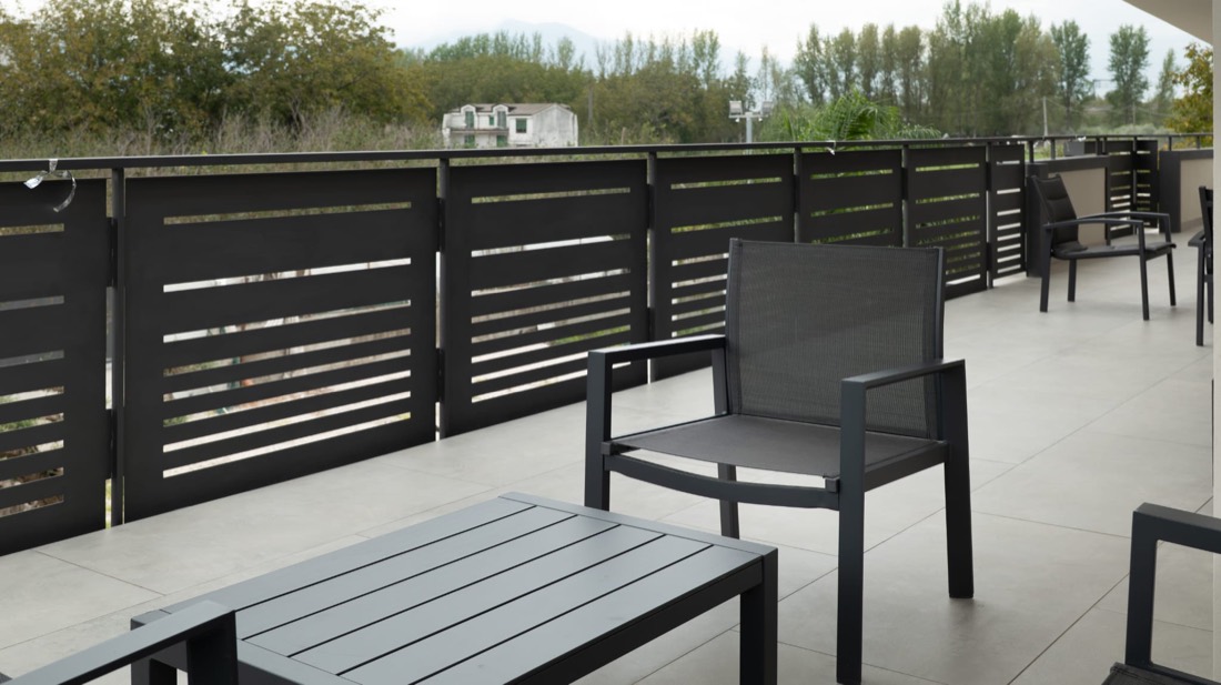 Ampia terrazza con poltrone in metallo nero, tavolino e vista sulle colline