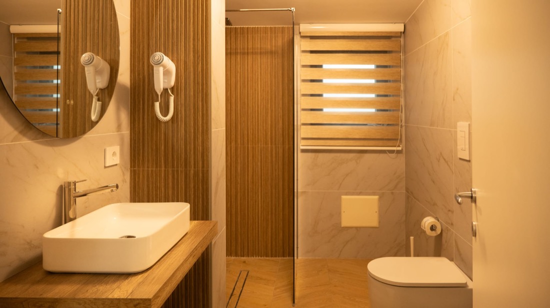Bagno moderno con parete a doghe, specchio tondo, lavabo d'appoggio e doccia walk-in