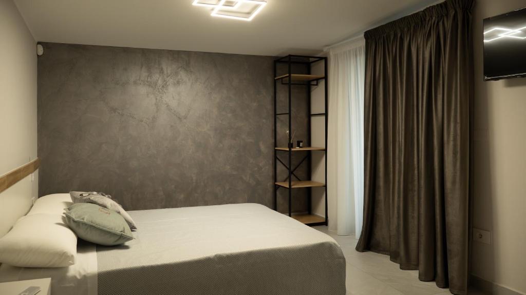 Suite Berlino: letto matrimoniale, parete in resina grigia, tende in velluto scuro e libreria in metallo nero