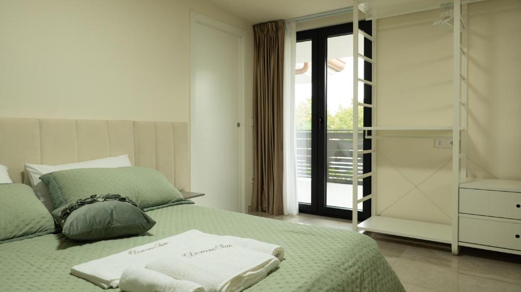 Suite Parigi: letto matrimoniale con testiera imbottita, biancheria verde salvia e porta-finestra sul balcone